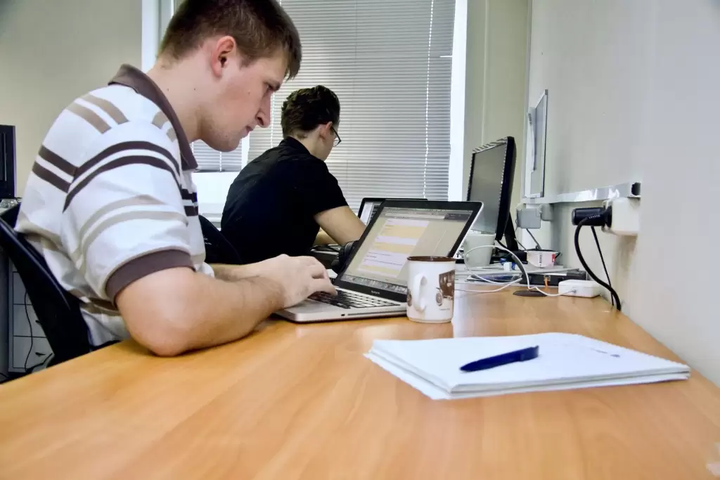 two people working on solving a problem on their pc